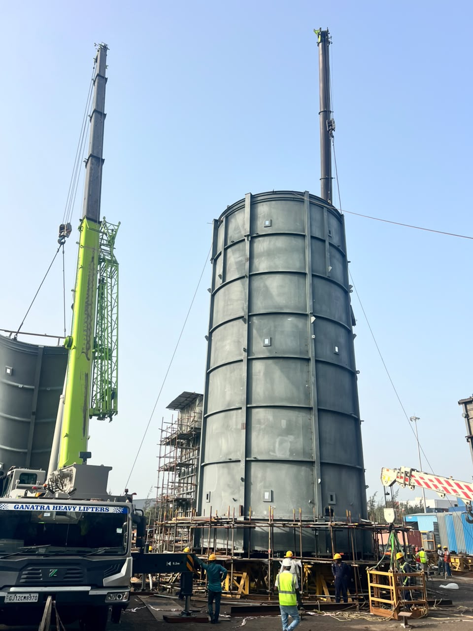 Green crane operating next to a large assembled cylindrical structure